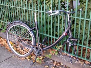 Fahrradfahren im Herbst und Winter, Kaputtes Fahrrad an einem Zaun