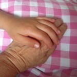 Kinderhand streichelt alte Hand