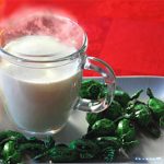 Hausmittel, Glas mit heißer Milch auf einem Tablett mit Hustenbonbons