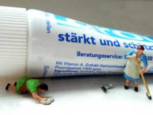 Miniatur-Hausfrauen vor Zahnpastatube