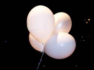 Vier weiße Luftballongs vor dunklem Himmel