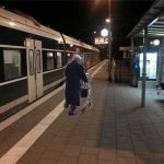 Alte Frau alleine auf einem Bahnsteig