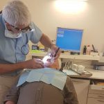 Eine deutsche Zahnarztpraxis auf Mallorca, Patient auf einem Zahnarztstuhl. Der Arzt beugt sich über ihn.